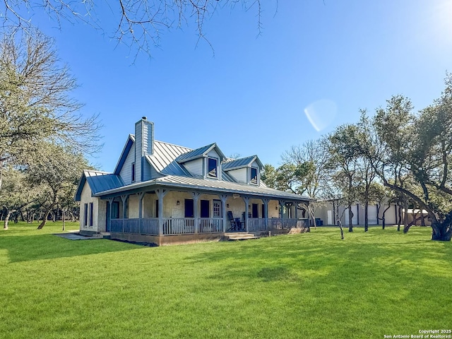 rear view of property with a standing seam roof, metal roof, covered porch, and a yard