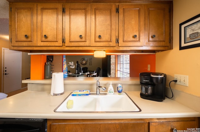 kitchen featuring light countertops, brown cabinetry, and a sink