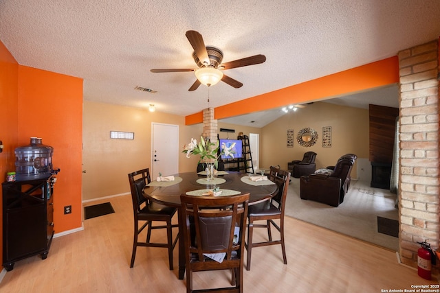 dining area with visible vents, light wood-style floors, vaulted ceiling, ceiling fan, and ornate columns