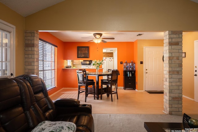 dining area with vaulted ceiling, decorative columns, light wood finished floors, and ceiling fan