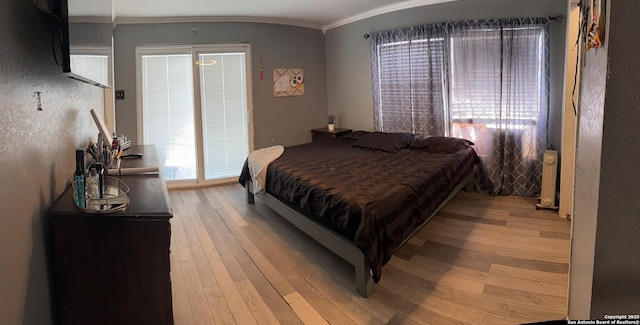 bedroom with crown molding and light wood finished floors