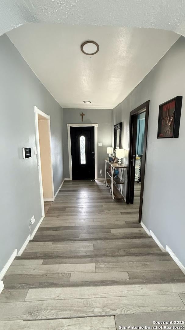 entrance foyer featuring a textured ceiling, baseboards, and wood finished floors