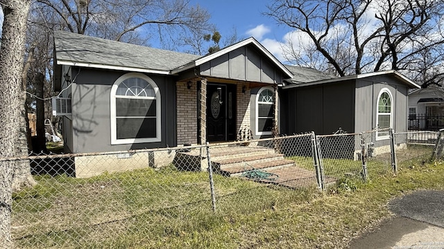 view of front of property with a fenced front yard, a front yard, roof with shingles, and brick siding