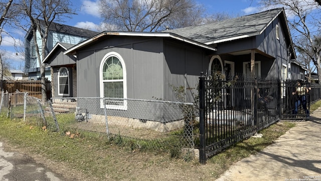 view of property exterior featuring a fenced front yard and roof with shingles