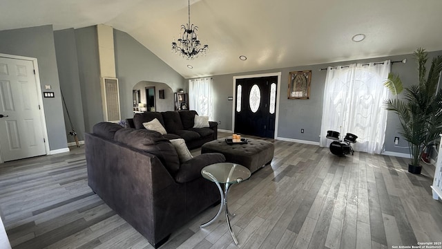 living area featuring arched walkways, baseboards, an inviting chandelier, and wood finished floors