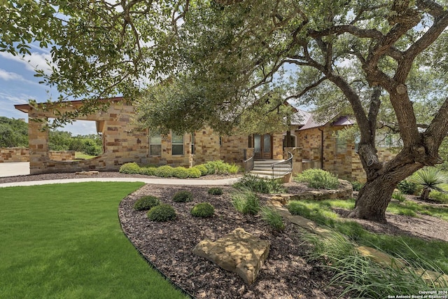 view of front of property featuring a front yard, stone siding, and metal roof