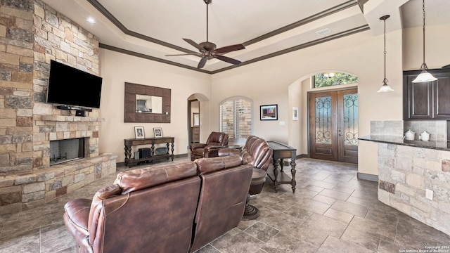 living room featuring arched walkways, a fireplace, visible vents, a tray ceiling, and crown molding