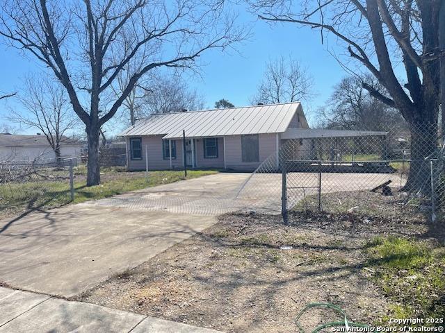 view of front facade featuring driveway, fence, and metal roof