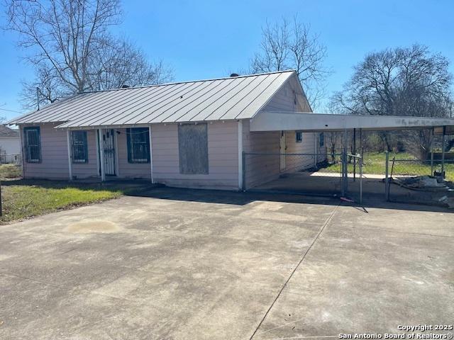 view of front of property with driveway, a standing seam roof, fence, and metal roof