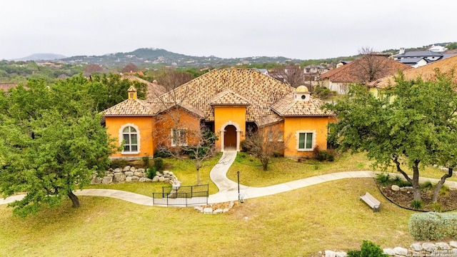 mediterranean / spanish-style home featuring stucco siding, a tile roof, and a front yard