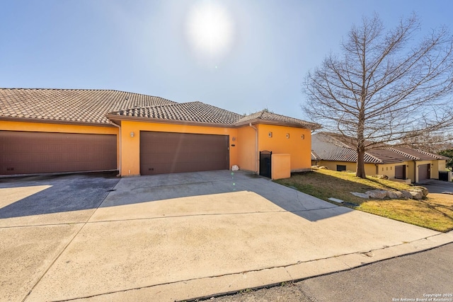 mediterranean / spanish home featuring driveway, a tile roof, a garage, and stucco siding