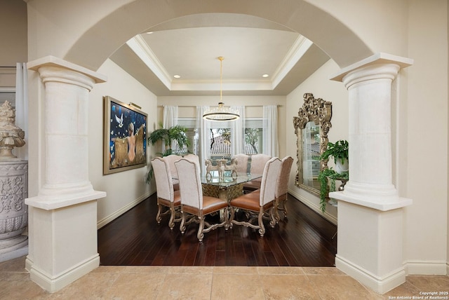 dining area featuring ornate columns, a tray ceiling, arched walkways, and ornamental molding