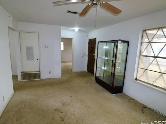 spare room featuring light carpet, a ceiling fan, visible vents, and baseboards