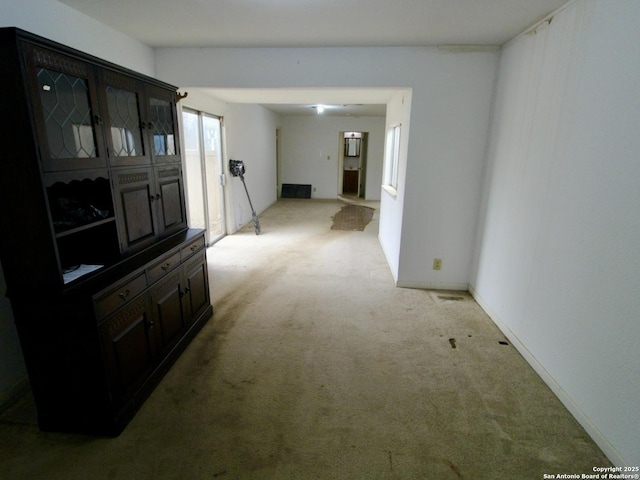 hallway featuring visible vents and light colored carpet