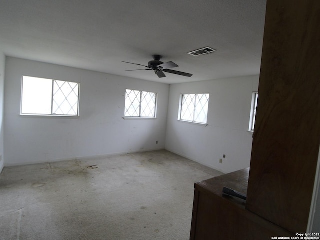 empty room featuring light colored carpet, visible vents, and ceiling fan