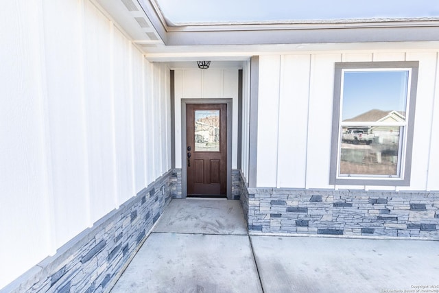 view of exterior entry with stone siding and board and batten siding