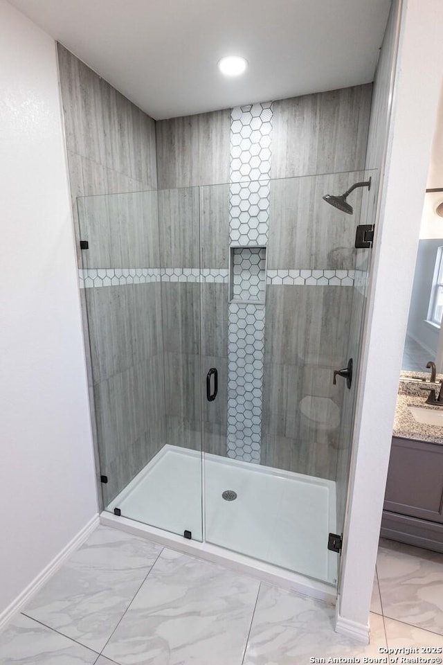 bathroom featuring marble finish floor, a stall shower, vanity, and baseboards