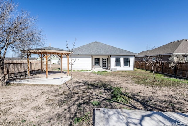 back of property with a gazebo, a shingled roof, a patio area, and a fenced backyard