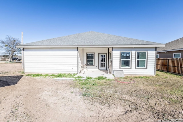 back of house with a patio, roof with shingles, and fence