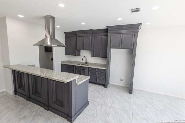 kitchen featuring visible vents, island range hood, light stone counters, marble finish floor, and a sink