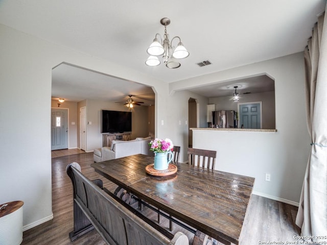 dining space with arched walkways, visible vents, dark wood finished floors, and baseboards