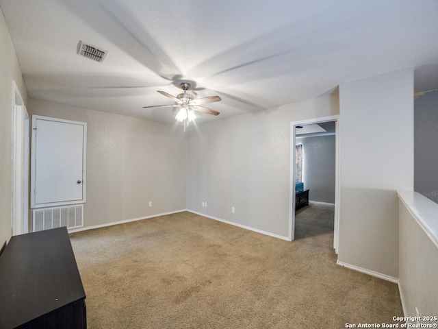 unfurnished room with carpet floors, visible vents, ceiling fan, and baseboards