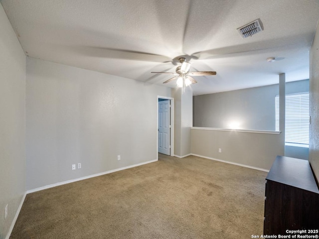 carpeted spare room with a ceiling fan, visible vents, and baseboards