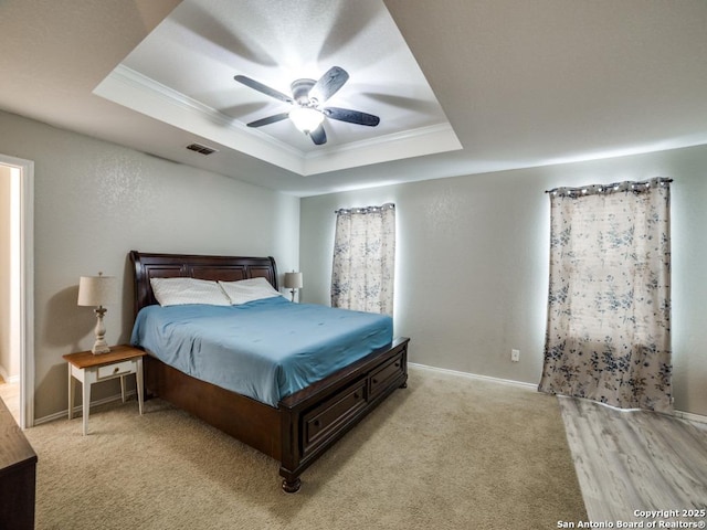 bedroom featuring ornamental molding, a raised ceiling, visible vents, and baseboards