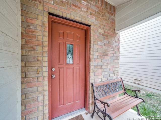 entrance to property featuring crawl space and brick siding