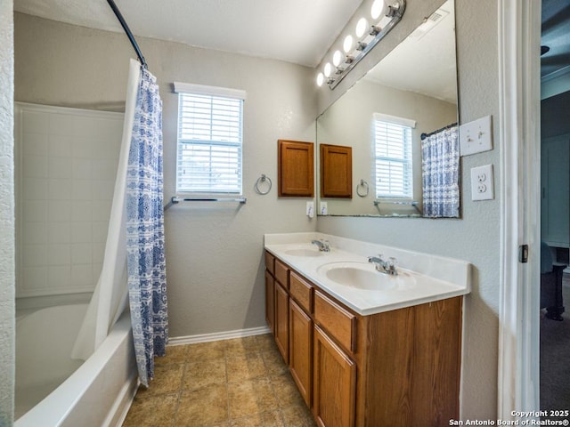 full bath with double vanity, baseboards, shower / bath combo with shower curtain, and a sink