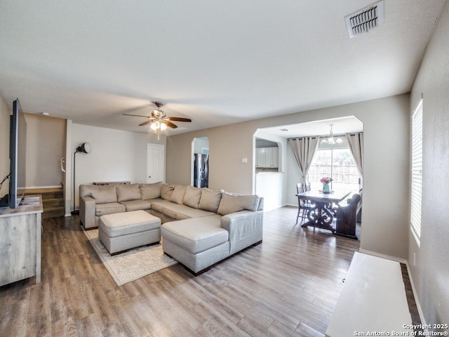 living room with baseboards, visible vents, wood finished floors, and ceiling fan with notable chandelier