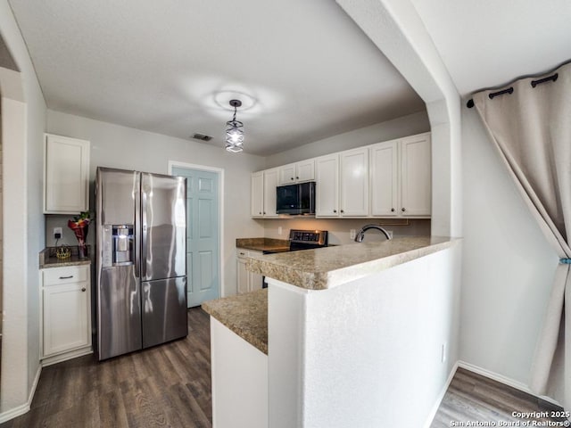 kitchen with dark wood finished floors, stainless steel appliances, hanging light fixtures, white cabinets, and a peninsula