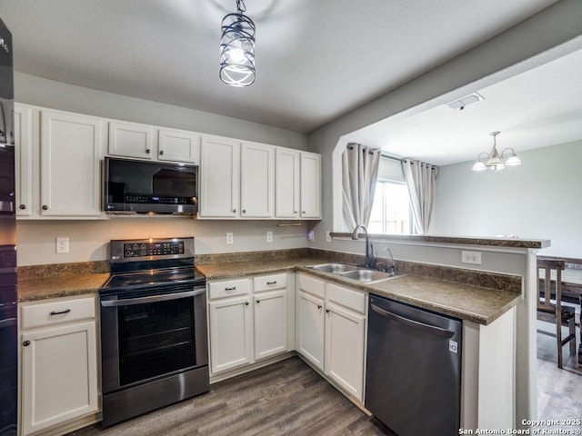 kitchen featuring stainless steel appliances, hanging light fixtures, dark countertops, and white cabinetry