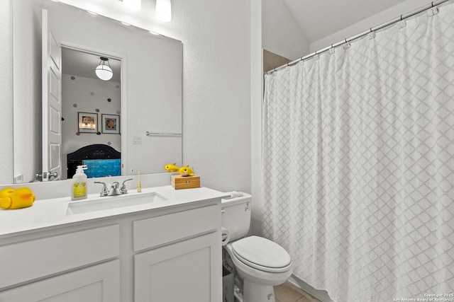 bathroom featuring ensuite bathroom, a textured wall, toilet, and vanity