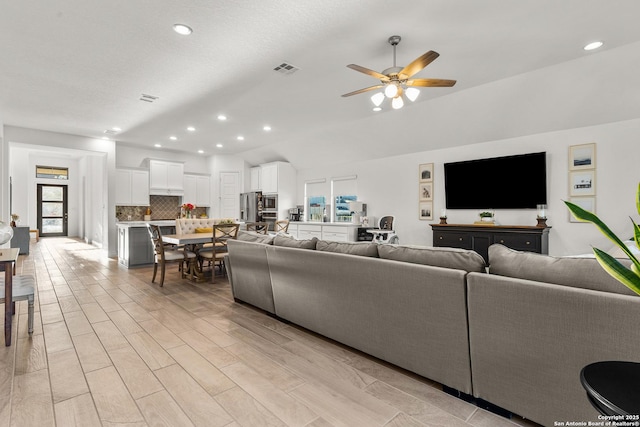 living area with a ceiling fan, recessed lighting, light wood-style flooring, and a textured ceiling