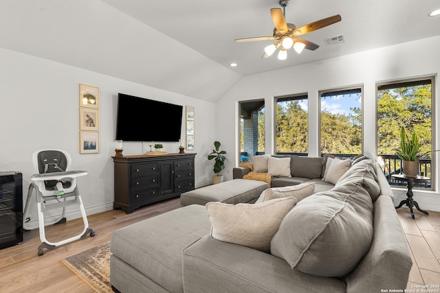 living room featuring light wood-type flooring, visible vents, vaulted ceiling, and a wealth of natural light