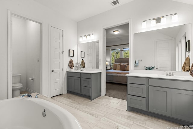 ensuite bathroom featuring ensuite bathroom, a washtub, toilet, vanity, and visible vents