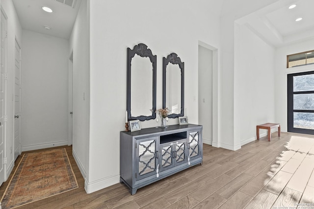 hallway with recessed lighting, visible vents, baseboards, and wood finished floors