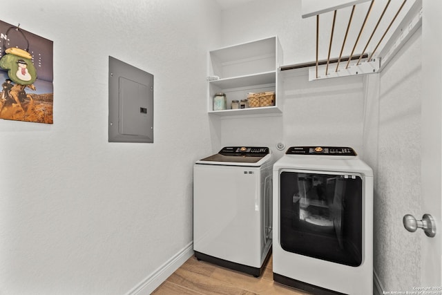 laundry area featuring laundry area, electric panel, baseboards, light wood-style floors, and separate washer and dryer