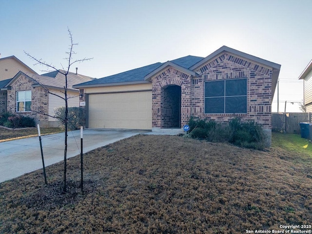 ranch-style home with concrete driveway, brick siding, fence, and an attached garage