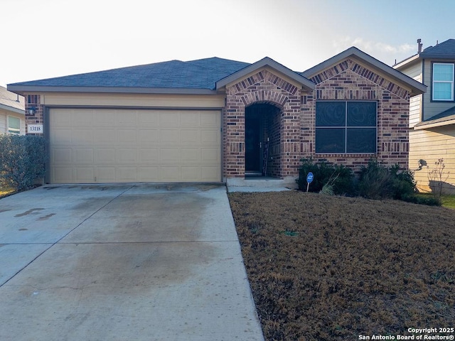 single story home featuring a garage, driveway, and brick siding