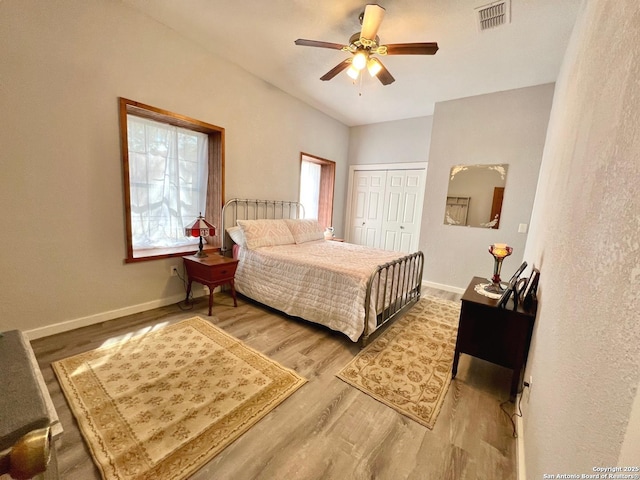 bedroom with a closet, wood finished floors, visible vents, and baseboards