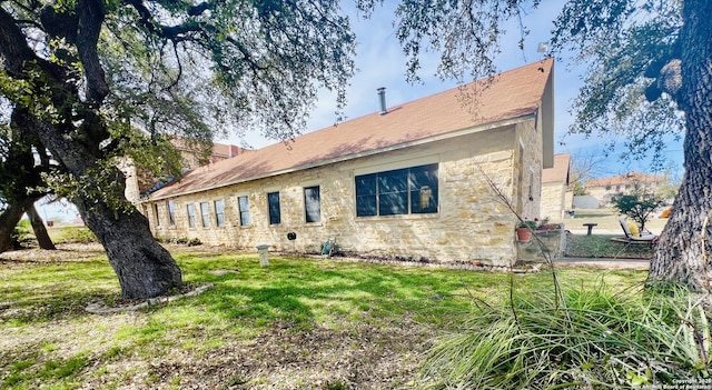 rear view of house featuring stone siding and a lawn