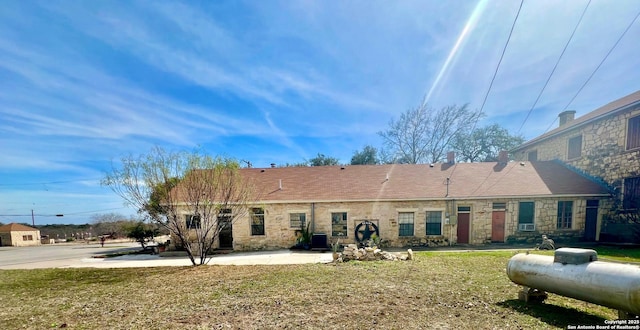 rear view of house featuring stone siding, a yard, and central air condition unit