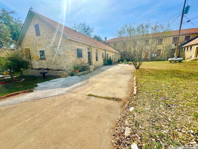 view of property exterior with stone siding and a yard