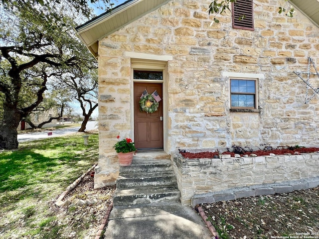 view of exterior entry featuring stone siding and visible vents