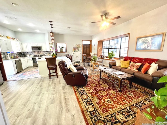 living room with ceiling fan, a textured ceiling, light wood-type flooring, and visible vents