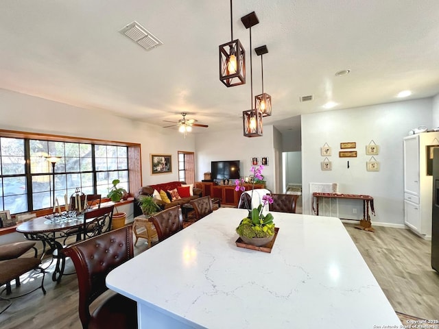 dining room featuring light wood finished floors, ceiling fan, and visible vents