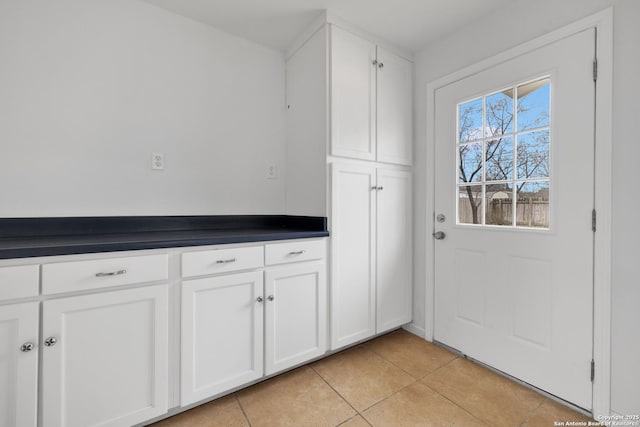 interior space featuring dark countertops, light tile patterned floors, and white cabinets