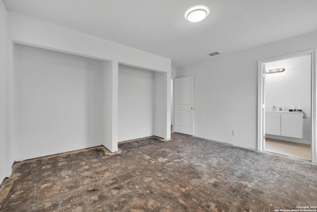 unfurnished bedroom featuring dark floors, visible vents, and ensuite bathroom